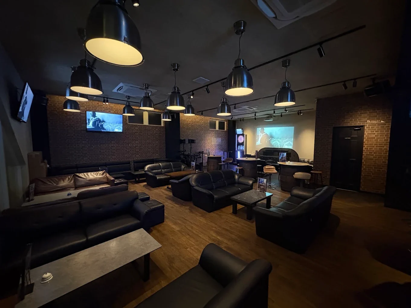 Cafe & BAR BUCKS のテーブル席。レンガの壁沿いにソファとテーブルが並ぶ広いラウンジ