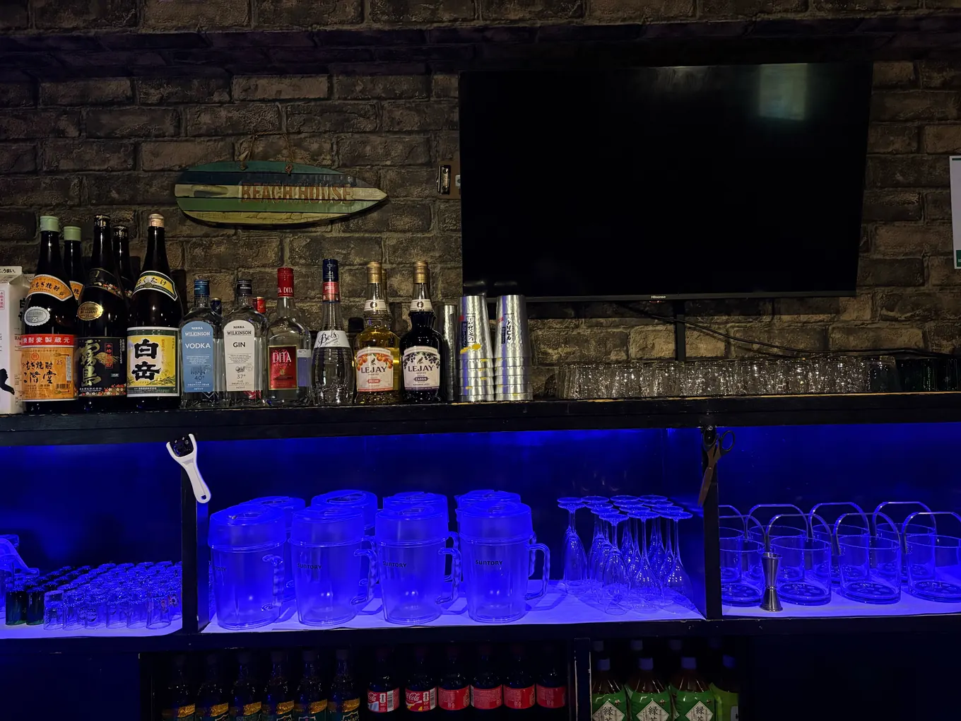 BAR Road のバックバー。棚に酒のボトルとグラスが並び、青い間接照明が灯っている