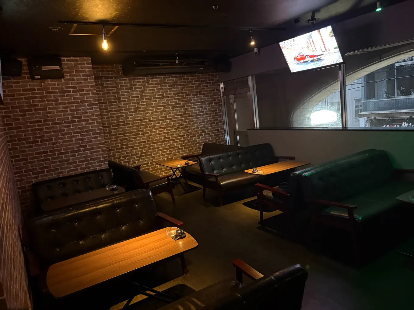 BAR Road の店内。レンガの壁沿いにソファ席とテーブルが並び、窓から外の明かりが入っている